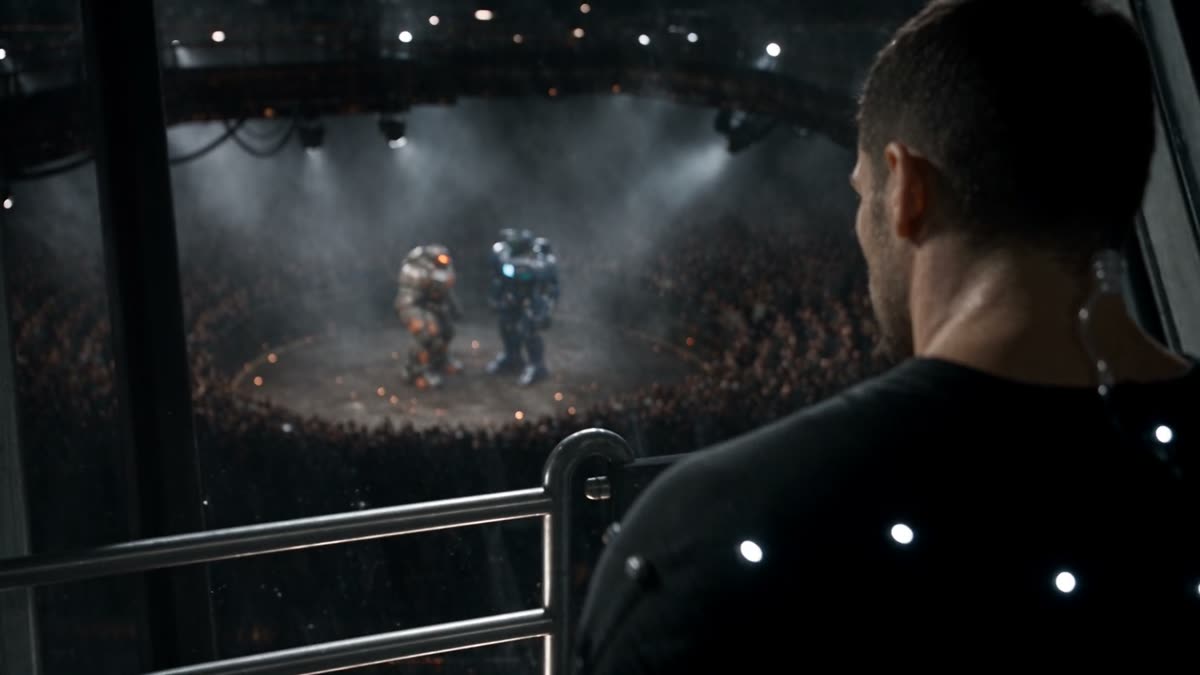 An operator in a motion-capture suit watching the robots from a protected booth